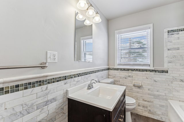 bathroom featuring plenty of natural light, tile walls, toilet, and vanity