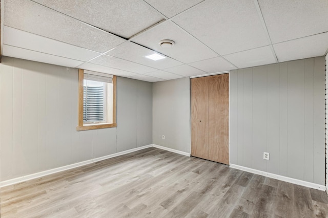 basement featuring a drop ceiling and light hardwood / wood-style floors