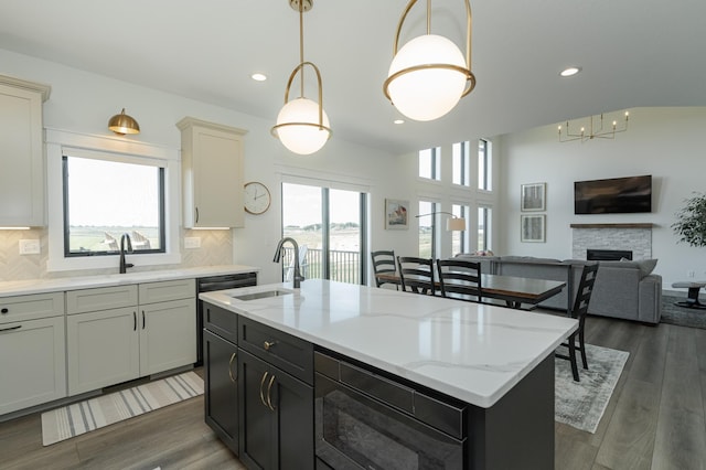 kitchen featuring a kitchen island with sink, pendant lighting, a sink, and open floor plan