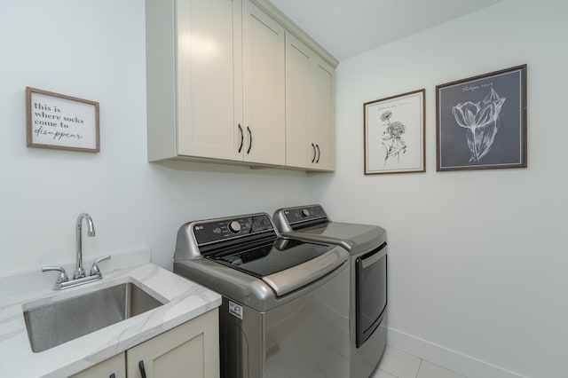 washroom with light tile patterned floors, washing machine and dryer, a sink, baseboards, and cabinet space