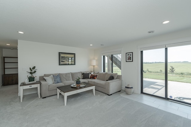 living area with light colored carpet, a rural view, recessed lighting, and light tile patterned flooring