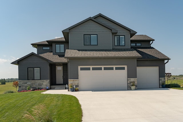 view of front of home with an attached garage, roof with shingles, driveway, and a front lawn