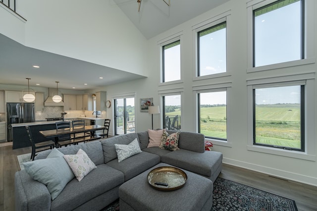 living area featuring high vaulted ceiling, dark wood-type flooring, recessed lighting, and baseboards