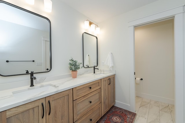 bathroom with marble finish floor, a sink, baseboards, and double vanity