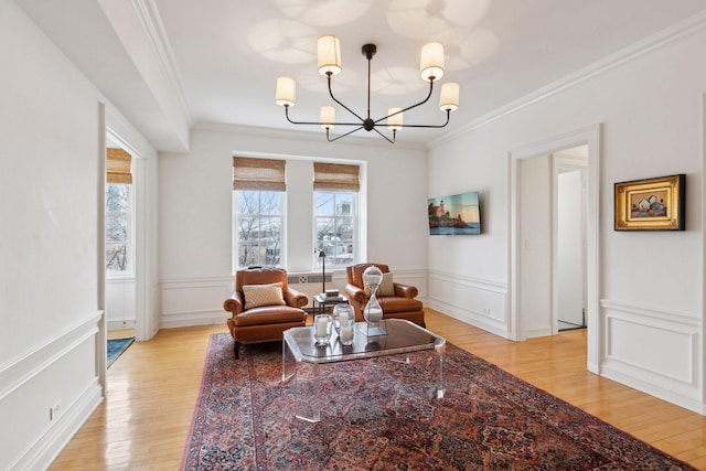 sitting room featuring light wood-type flooring, a notable chandelier, and ornamental molding