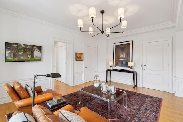 living room with ornamental molding, light hardwood / wood-style flooring, and a notable chandelier