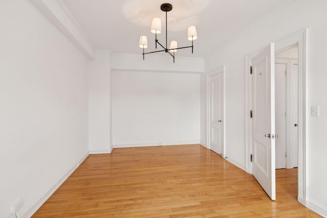 unfurnished dining area featuring light wood-type flooring, ornamental molding, and an inviting chandelier