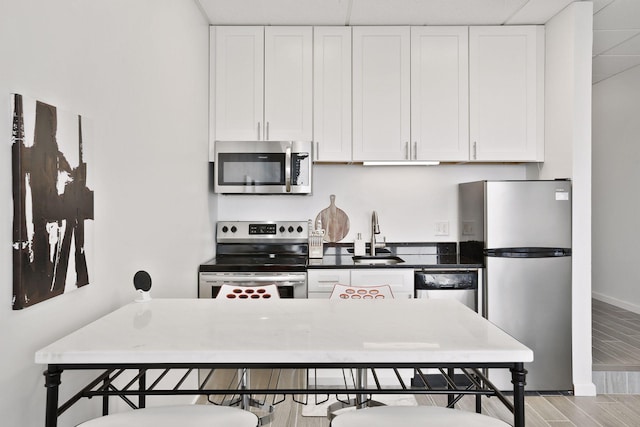 kitchen with stainless steel appliances, white cabinetry, and sink