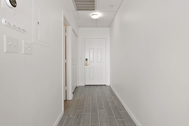 hallway with a paneled ceiling and wood-type flooring