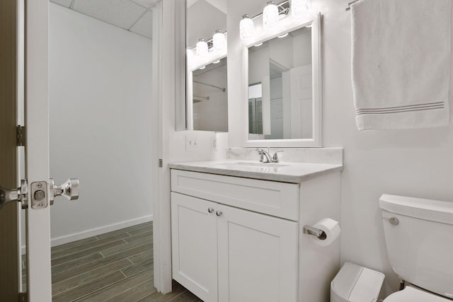 bathroom with a drop ceiling, toilet, and vanity