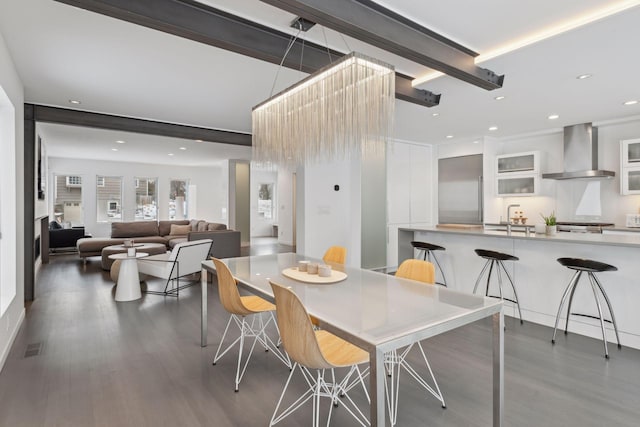 dining space with sink, beamed ceiling, and dark hardwood / wood-style floors