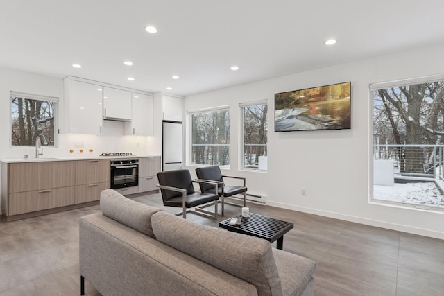 living room featuring baseboard heating, a healthy amount of sunlight, and sink