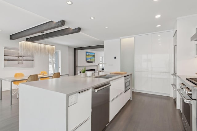 kitchen with dark wood-type flooring, a center island with sink, white cabinetry, appliances with stainless steel finishes, and sink