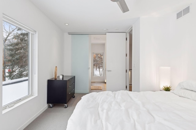 carpeted bedroom with ceiling fan, multiple windows, and radiator