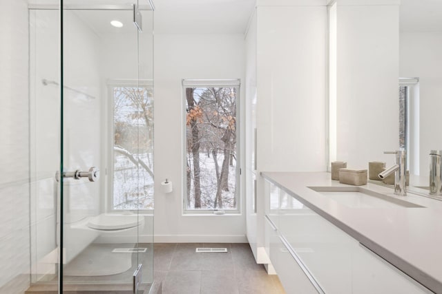 bathroom featuring toilet, vanity, tile patterned flooring, and a shower with shower door