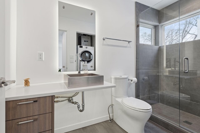 bathroom featuring stacked washer and dryer, an enclosed shower, toilet, and vanity