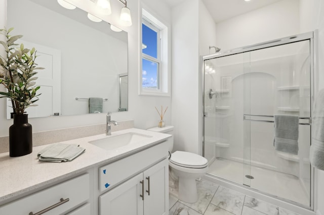 bathroom featuring a shower with door, vanity, and toilet