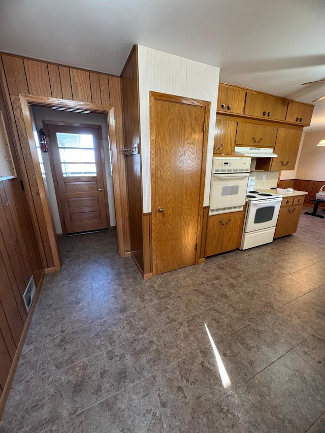 kitchen with white appliances, wood walls, and ceiling fan