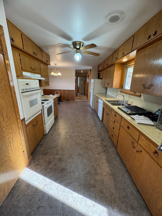 kitchen with white appliances, hanging light fixtures, sink, backsplash, and ceiling fan with notable chandelier