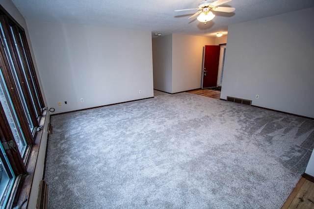 empty room featuring carpet flooring, ceiling fan, and a textured ceiling