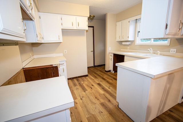 kitchen with light hardwood / wood-style floors, white cabinetry, and sink