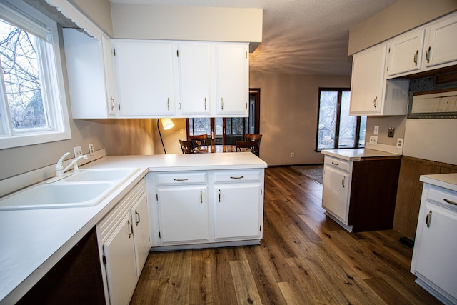 kitchen featuring white cabinets, dark hardwood / wood-style floors, kitchen peninsula, and sink