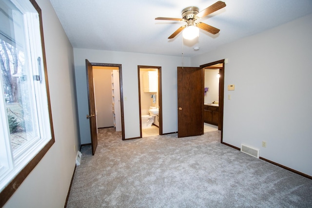 unfurnished bedroom featuring ceiling fan, light colored carpet, and connected bathroom