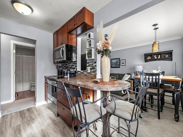 kitchen with backsplash, decorative light fixtures, stainless steel appliances, and light hardwood / wood-style floors