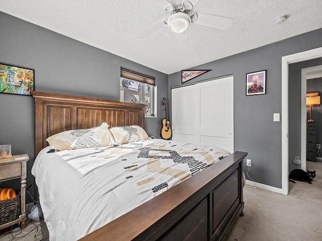 carpeted bedroom with ceiling fan, a textured ceiling, and a closet