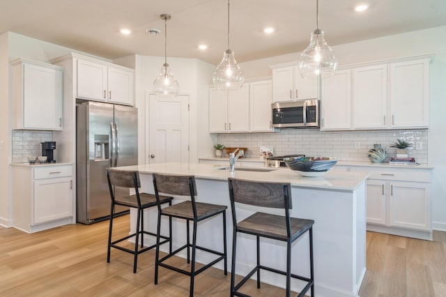 kitchen featuring sink, white cabinetry, stainless steel appliances, and hanging light fixtures