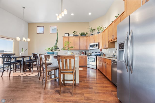 kitchen with appliances with stainless steel finishes, a chandelier, pendant lighting, and a kitchen bar