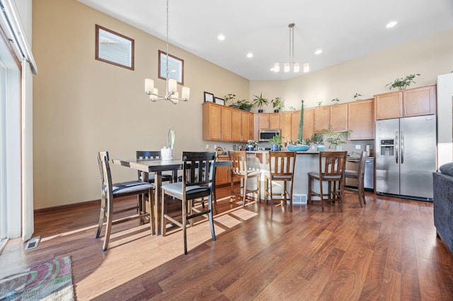 kitchen with appliances with stainless steel finishes, a notable chandelier, dark hardwood / wood-style flooring, a high ceiling, and decorative light fixtures