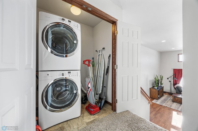 laundry room with light wood-type flooring and stacked washer / dryer