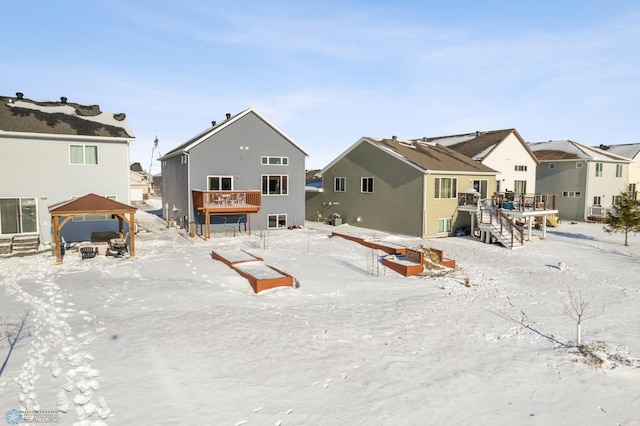 snow covered back of property with a deck and a gazebo