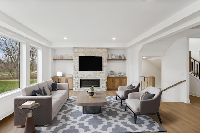 living room with a stone fireplace and wood-type flooring