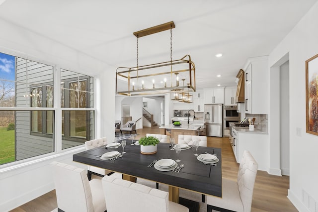 dining room with hardwood / wood-style floors, an inviting chandelier, and sink