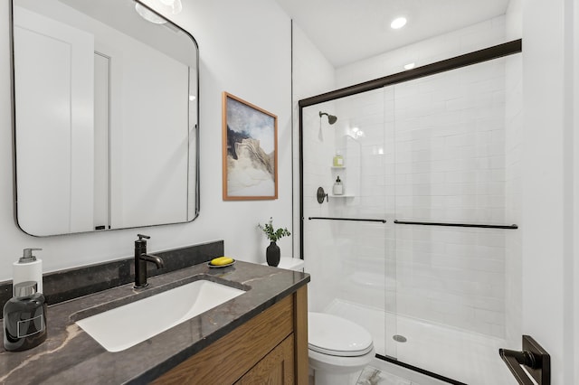 bathroom with vanity, toilet, and a shower with door