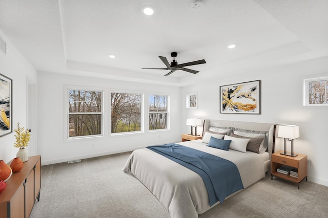 carpeted bedroom with a tray ceiling and ceiling fan