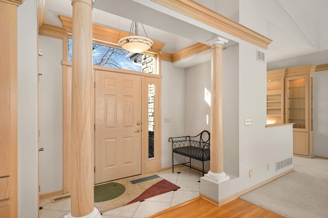 tiled entrance foyer with visible vents, decorative columns, and baseboards