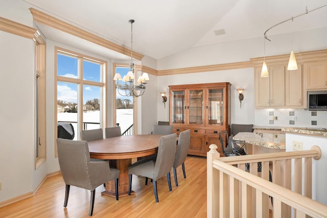 dining area with light wood-type flooring, high vaulted ceiling, and a chandelier