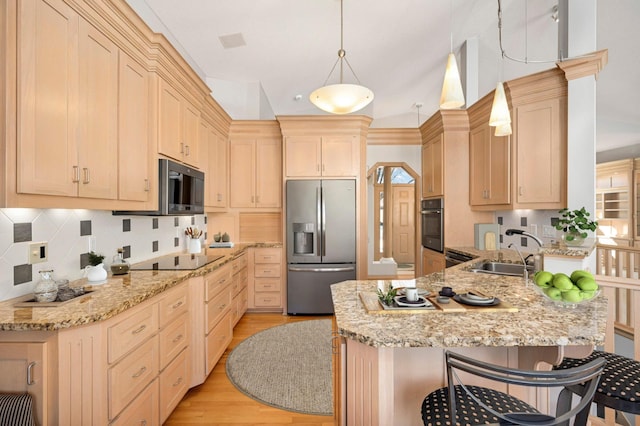 kitchen with a peninsula, a sink, a kitchen breakfast bar, black appliances, and light wood finished floors