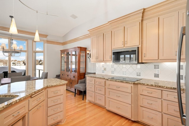 kitchen featuring light wood finished floors, stainless steel microwave, vaulted ceiling, black electric cooktop, and light brown cabinetry