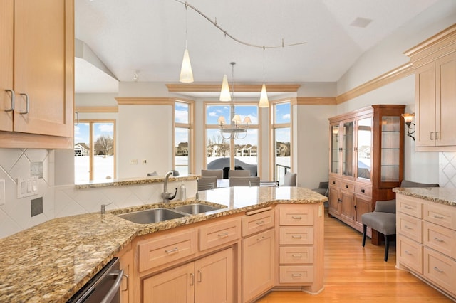 kitchen featuring light wood-style flooring, light brown cabinetry, vaulted ceiling, a sink, and light stone countertops