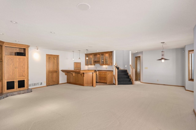 unfurnished living room with stairs, light carpet, visible vents, and baseboards