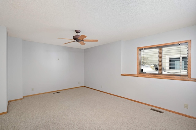 spare room featuring baseboards, visible vents, a textured ceiling, and carpet flooring