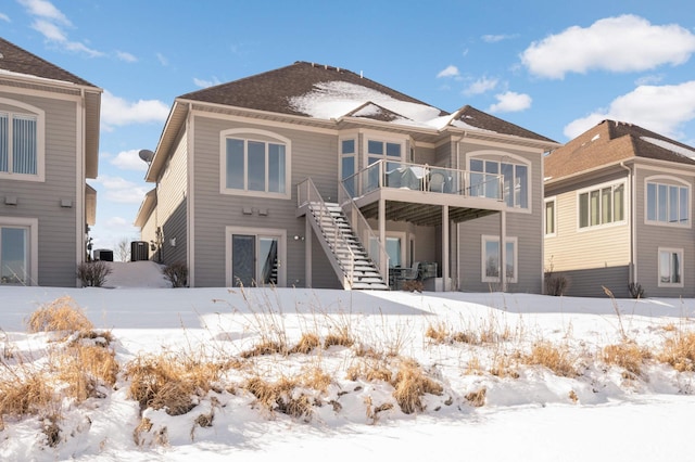 snow covered rear of property with stairway