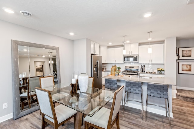 dining room featuring sink, light hardwood / wood-style floors, and a textured ceiling