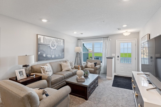 living room featuring a textured ceiling, plenty of natural light, and light carpet