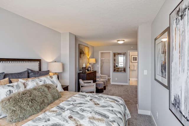 carpeted bedroom featuring a walk in closet, a textured ceiling, and a closet