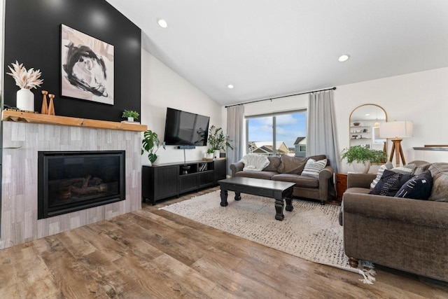 living room featuring a glass covered fireplace, vaulted ceiling, recessed lighting, and wood finished floors